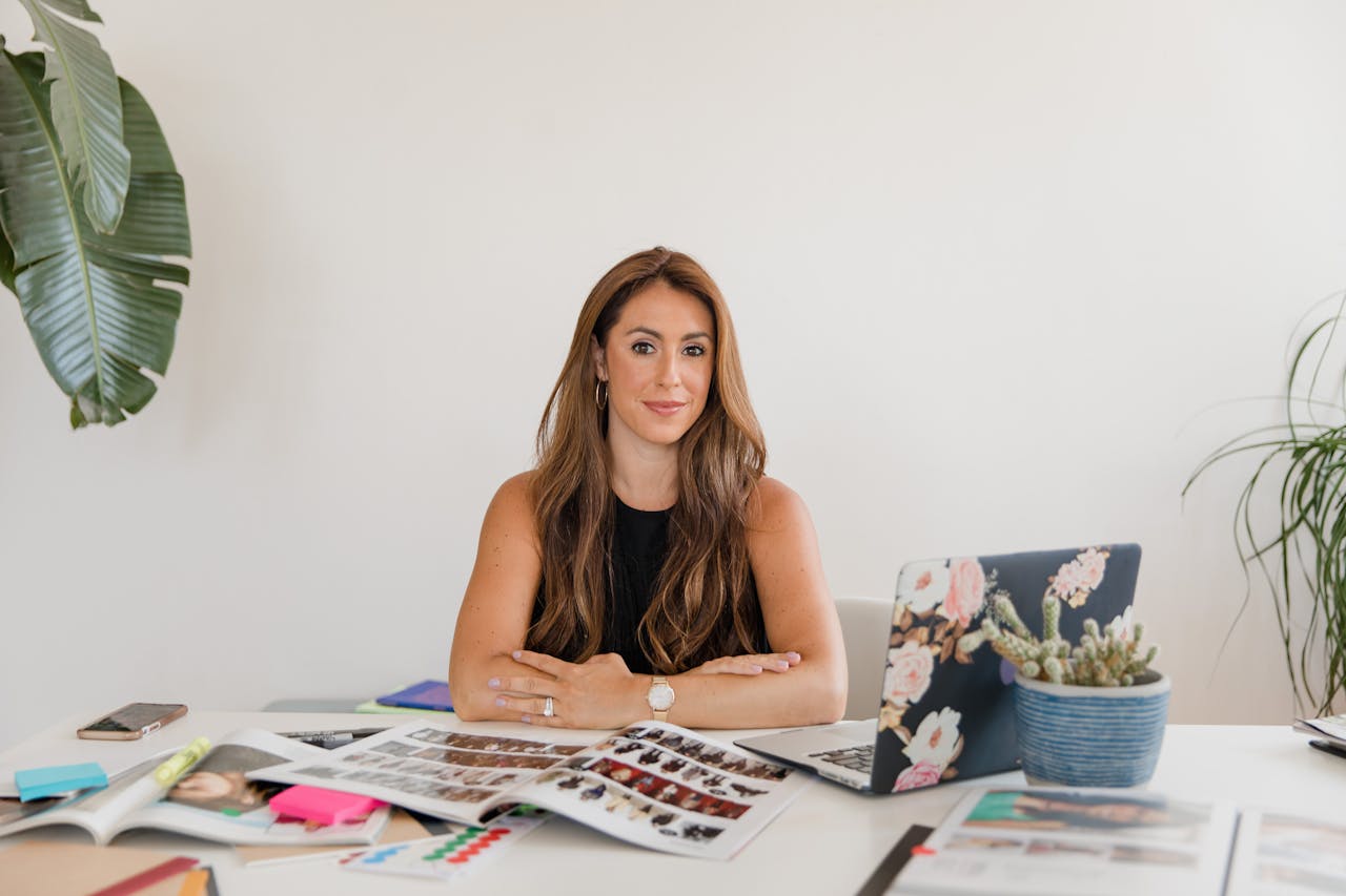 Successful businesswoman posing confidently at her office desk surrounded by work materials.